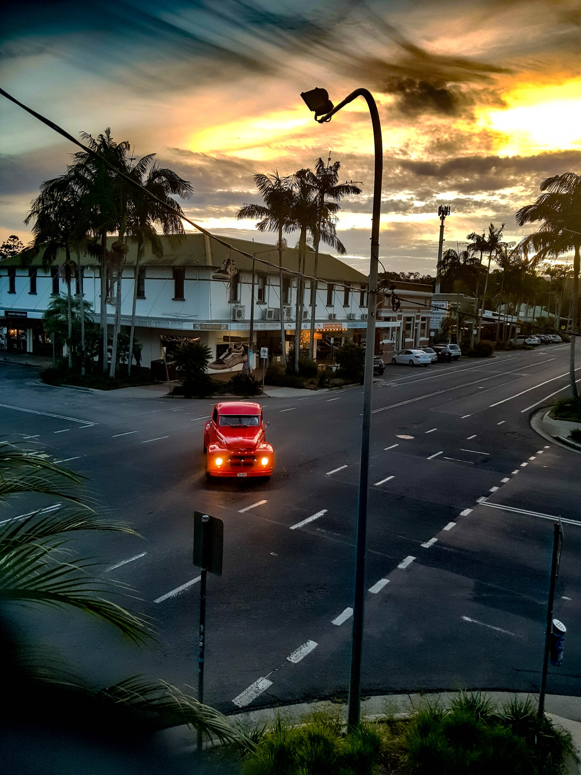 An old red car turning on an intersection